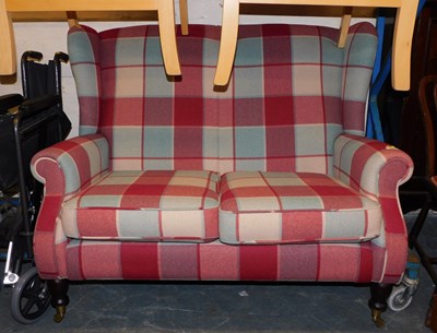 Lot 1020 - A compact two-seater wing back sofa, raised on...