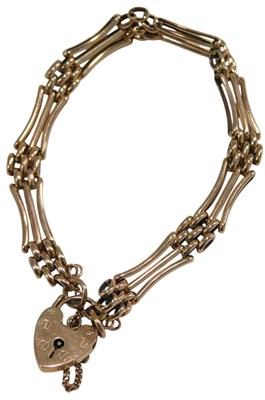 Lot 1045 - A 9ct rose gold three bar gate bracelet, on a...