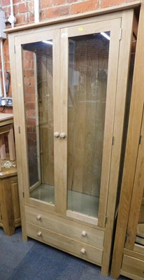 Lot 1002 - A light oak cabinet, of two glazed doors over...