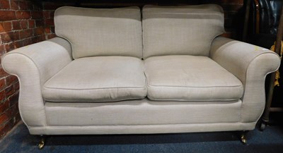 Lot 1028 - A beige upholstered two seater sofa.