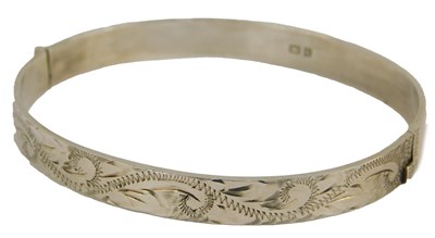 Lot 221 - A silver bangle, with engraved foliate...