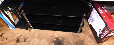 Lot 1047 - A black glass three tier television stand,...