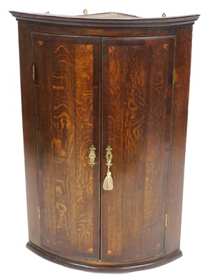 Lot 509 - A George III oak bow front hanging corner...