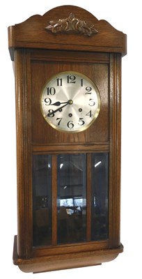 Lot 128 - A 1920s oak wall clock, the silvered dial with...