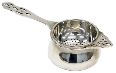 Lot 21 - A George V silver tea strainer and stand, with...