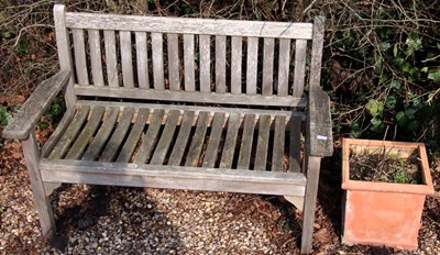 Lot 1655 - A teak two seater garden bench, with slatted...
