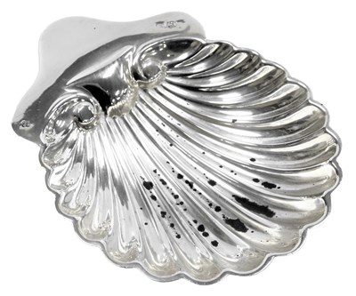 Lot 106 - A silver scallop shell butter dish, raised on...