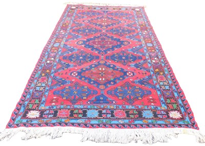 Lot 877 - An Afghan red ground rug, the central field...