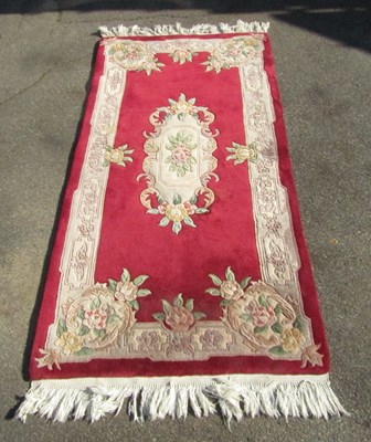Lot 1022 - A red ground Chinese rug, with floral motifs.