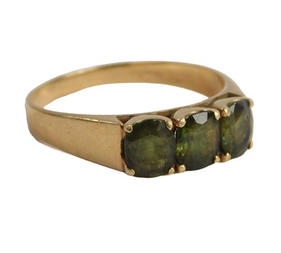 Lot 600 - A moldavite three stone ring, claw set, yellow...