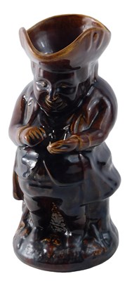 Lot 185 - A 19thC treacle glazed pottery snuff Toby jug,...