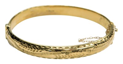 Lot 574 - A 9ct gold bangle, with engraved foliate...
