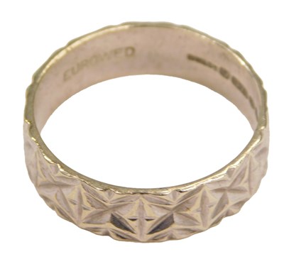 Lot 565 - A 9ct white gold wedding band, with engraved...