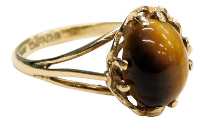Lot 614 - A 9ct gold and tigers eye cabochon ring, in a...