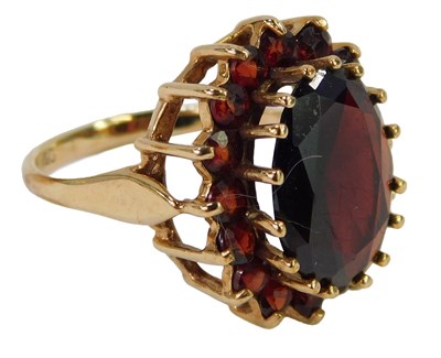 Lot 448 - A garnet cluster ring, the oval central garnet...
