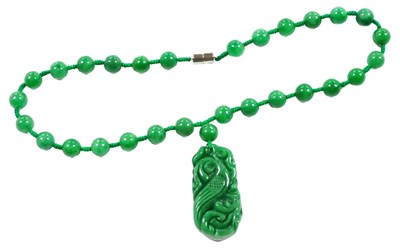 Lot 554 - A green jade necklace, with a pendant carved...