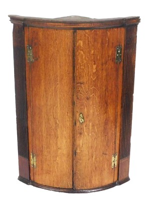 Lot 730 - A George III oak bow front corner cupboard,...