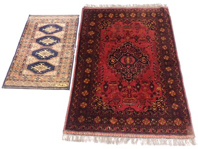 Lot 819 - An Afghan red ground rug, the central field...