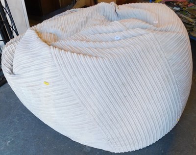 Lot 1104 - A large bean bag, upholstered in beige fabric,...
