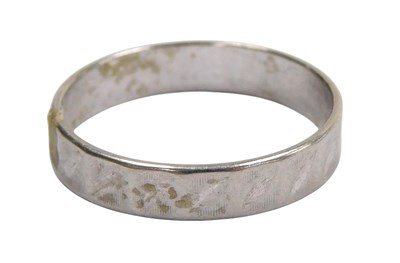 Lot 565 - A faceted wedding band, white metal stamped...
