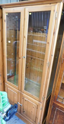 Lot 1135 - A varnished pine display cabinet, with two...