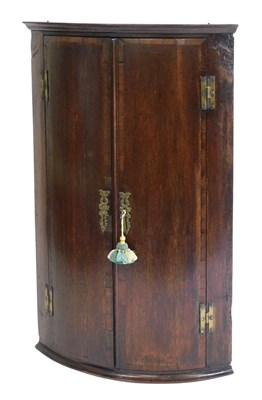 Lot 466 - A George III oak bow front hanging corner...