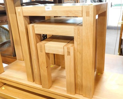 Lot 1506 - A contemporary light oak nest of three tables,...