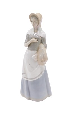 Lot 619 - A large porcelain figure of a lady carrying...