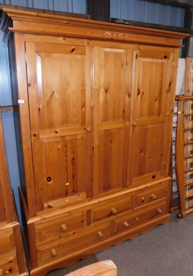 Lot 1010 - A pine triple wardrobe, the top with a moulded...