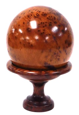 Lot 434 - A burl thuya wood sphere, on a stand, 26cm high.