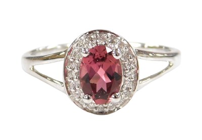 Lot 228 - A ruby and diamond cluster ring, the pale oval...