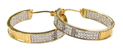Lot 561 - A pair of gold plate and diamond creole earrings.