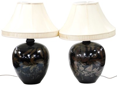 Lot 704 - A pair of black glazed pottery table lamps,...