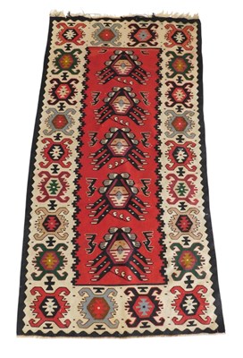Lot 748 - A Kilim red ground rug, the central field with...