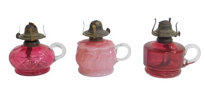 Lot 520 - Two cranberry glass finger oil lamps, together...
