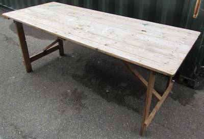 Lot 1103 - A wooden pine trestle table, with folding legs.