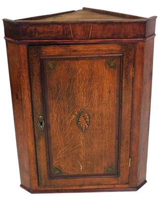 Lot 525 - A George III oak hanging corner cupboard, with...