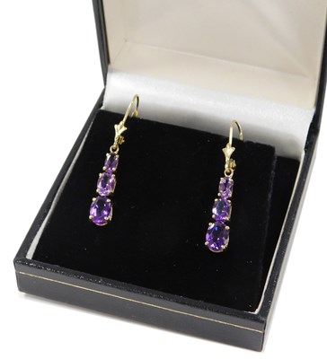 Lot 414 - A pair of graduated amethyst triple drop...