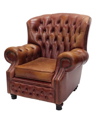 Lot 919 - A brown buttoned leather wing back chair, on...