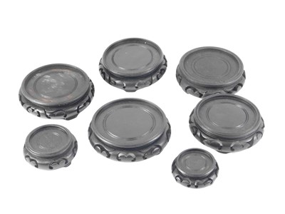 Lot 157 - Seven Oriental ebonised vase stand bases, the...