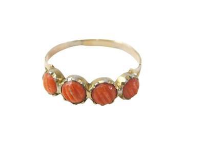 Lot 89 - A four stone coral dress ring, on a silver...